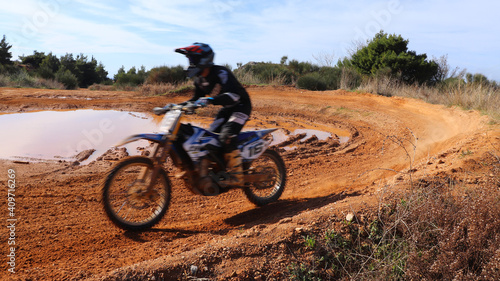 Professional dirt bike motocross rider performing stunts in extreme mud terrain track