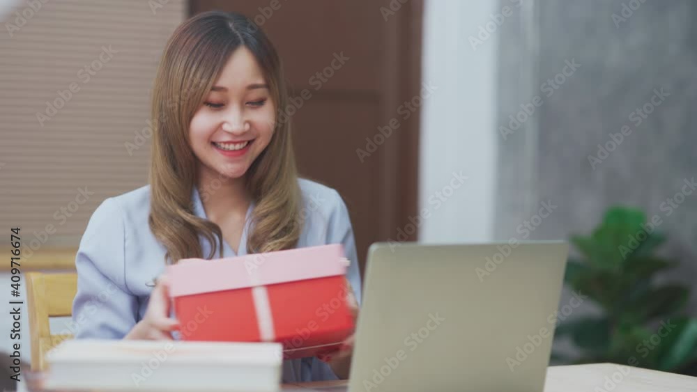 Asian young woman got present giftbox from her boyfriend while talking with laptop for new normal concept Asian young woman got present giftbox from her boyfriend while talking with laptop for new normal concept