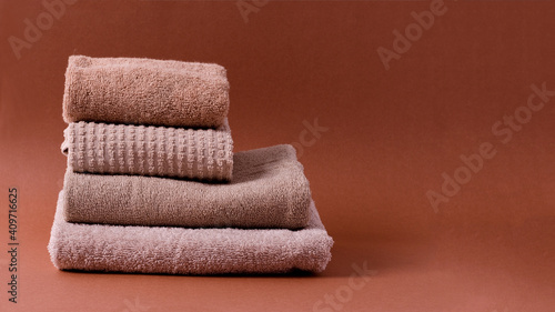 A stack of cotton clean brown-hued towels on a brown background.