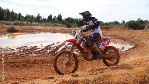 Professional dirt bike motocross rider performing stunts in extreme terrain track
