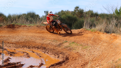 Professional dirt bike motocross rider performing stunts in extreme mud terrain track