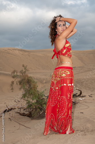 Arab belly dancer in the desert at sunset