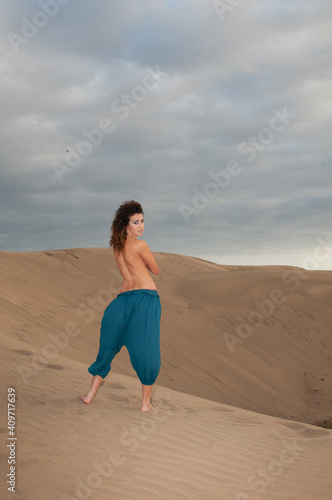 Arab belly dancer in the desert at sunset