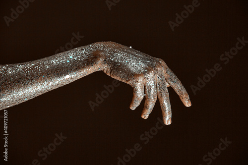 Silver sparkling body art  close up of female hand  woman s arm in sparkles  skincare concept