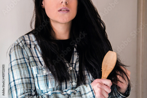 Mujer joven cepillándose su pelo largo y moreno. Concepto de caída del cabello photo