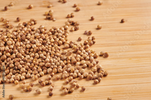 Heap of dry coriander seeds on a wooden background. Close up view.