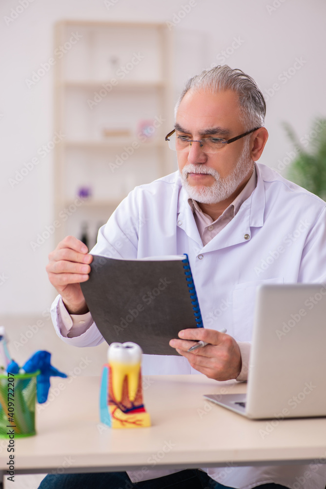 Old male dentist working in the clinic Old male dentist working in the clinic