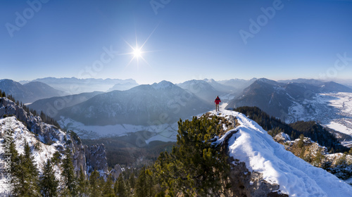 Hiker in red jacket on top of snow covered mountain