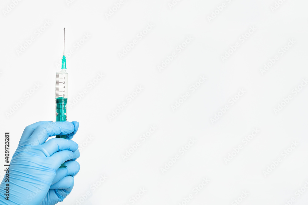 A doctor's hand in a medical glove holds a syringe with a needle to protect against the flu virus. Cvd vaccine. The concept of medicine vaccination treatment with subcutaneous injections, copy space A doctor's hand in a medical glove holds a syringe with a needle to protect against the flu virus. Cvd vaccine. The concept of medicine vaccination treatment with subcutaneous injections, copy space