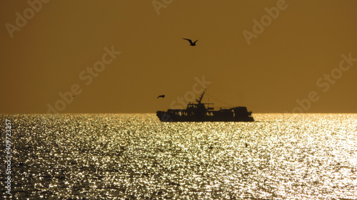 Beautiful ocean sunset, with colorful clouds, blue ocean and the silhouette of a ship on the horizon.