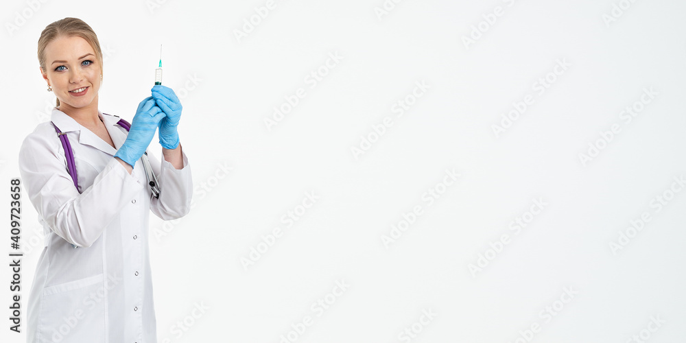 A young nurse in a mask and white coat holds a syringe with a needle for injections, flu shots, covid. The concept of vaccination and protection against influenza, from a pandemic. copy space. banner A young nurse in a mask and white coat holds a syringe with a needle for injections, flu shots, covid. The concept of vaccination and protection against influenza, from a pandemic. copy space. banner
