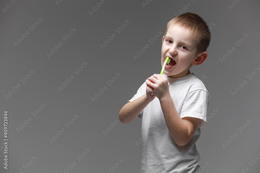 Happy child kid boy brushing teeth with toothbrush on gray background. Health care, dental hygiene. Mockup, copy space Happy child kid boy brushing teeth with toothbrush on gray background. Health care, dental hygiene. Mockup, copy space