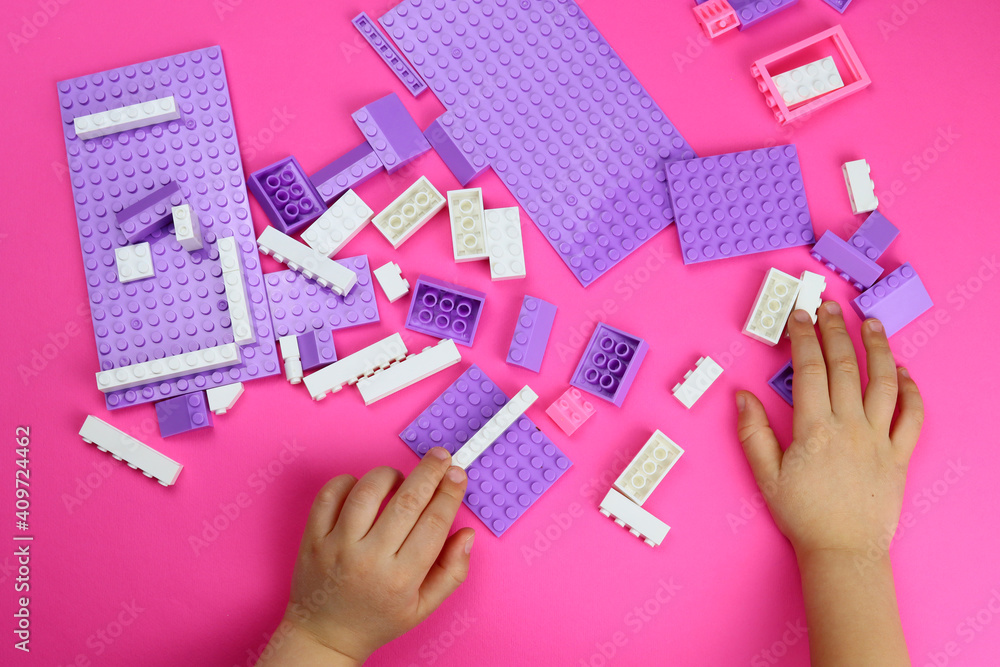 Naklejka premium child plays with colored toy blocks on a pink table