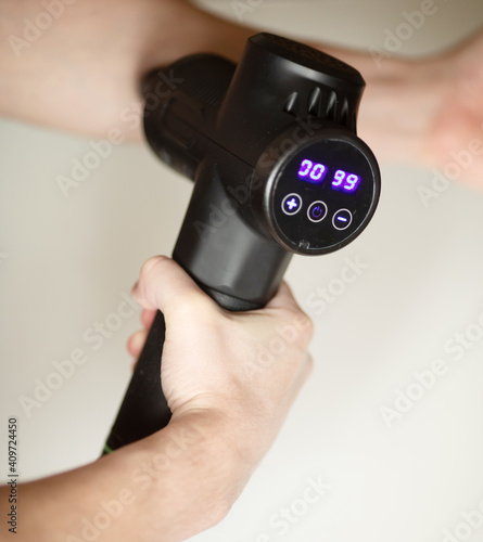 Man massaging his hand with massage percussion device after workout.