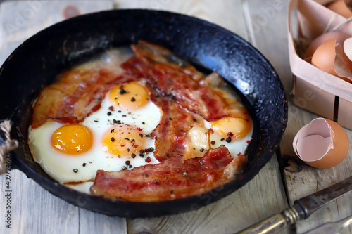 Scrambled eggs with bacon in a frying pan. Traditional delicious breakfast. Juicy appetizing scrambled eggs with bacon.