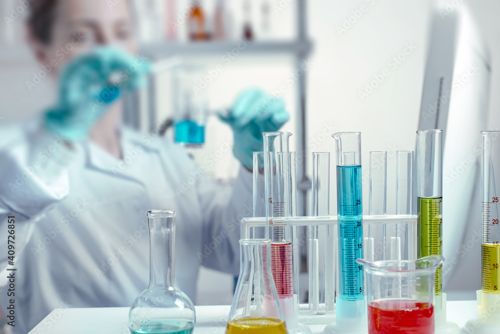 laboratory equipment, supplies, jars, bottles, cylinders, beakers, graduate, test-mixer, medicine-glass. Scientist pouring liquid into beakers in a chemical laboratory in defocus laboratory equipment, supplies, jars, bottles, cylinders, beakers, graduate, test-mixer, medicine-glass. Scientist pouring liquid into beakers in a chemical laboratory in defocus