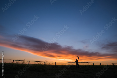 Silhouette of a man with a bouquet on the background of dawn.