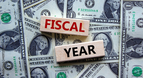 Fiscal year symbol. Concept words 'fiscal year' on wooden blocks on a beautiful background from dollar bills. Business and fiscal year concept.