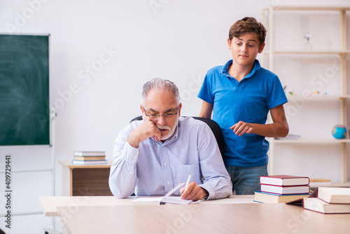 Old male teacher and schoolboy in the classroom