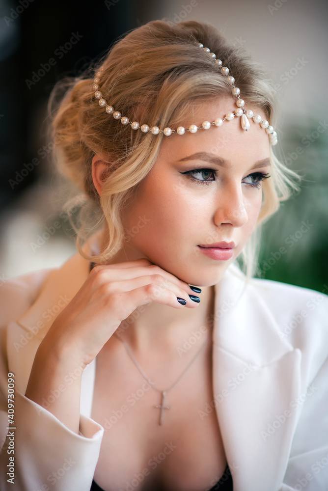 Beautiful blonde woman in white jacket. Beauty portrait with pearls in hairstyle