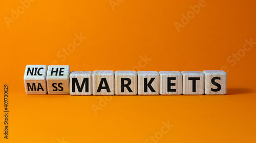 Mass or niche markets symbol. Turned wooden cubes and changed words 'mass markets' to 'niche markets'. Beautiful orange background, copy space. Business and mass or niche markets concept.