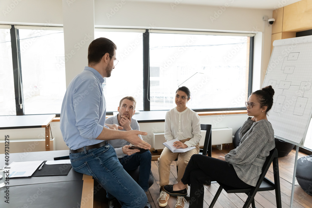 Diverse business group discussing project strategy in boardroom. Office colleagues talking and planning work tasks at meeting. Mentor teaching interns or new employees. Teamwork or workshop concept Diverse business group discussing project strategy in boardroom. Office colleagues talking and planning work tasks at meeting. Mentor teaching interns or new employees. Teamwork or workshop concept