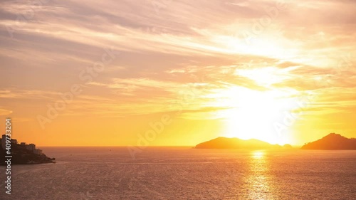 Timelapse with beautiful views of the peaceful ocean at mountainous sunset and clear skies with the setting sun. Sunset video concept. Vacation concept.