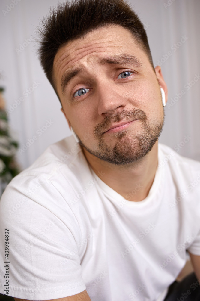 portrait of sad young man in earphones is talking to somebody on video call. portrait of sad young man in earphones is talking to somebody on video call.