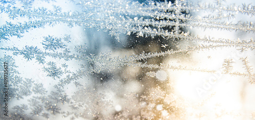 frosty pattern on the window with blue sky and yellow sun. soft focus. macro