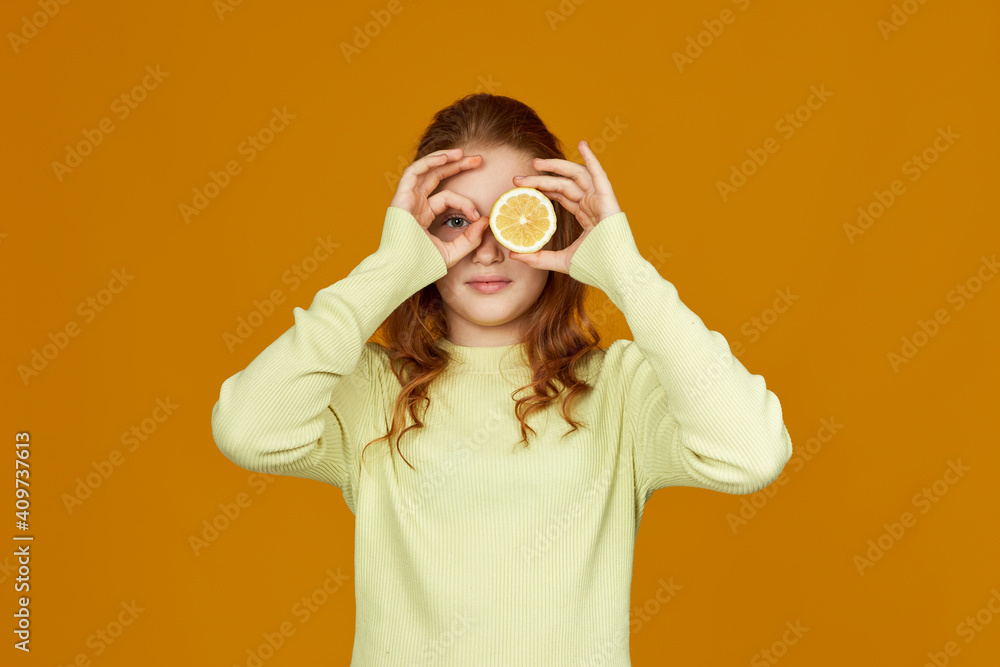Fototapeta premium little child girl holding fresh juicy lemon isolated on yellow background