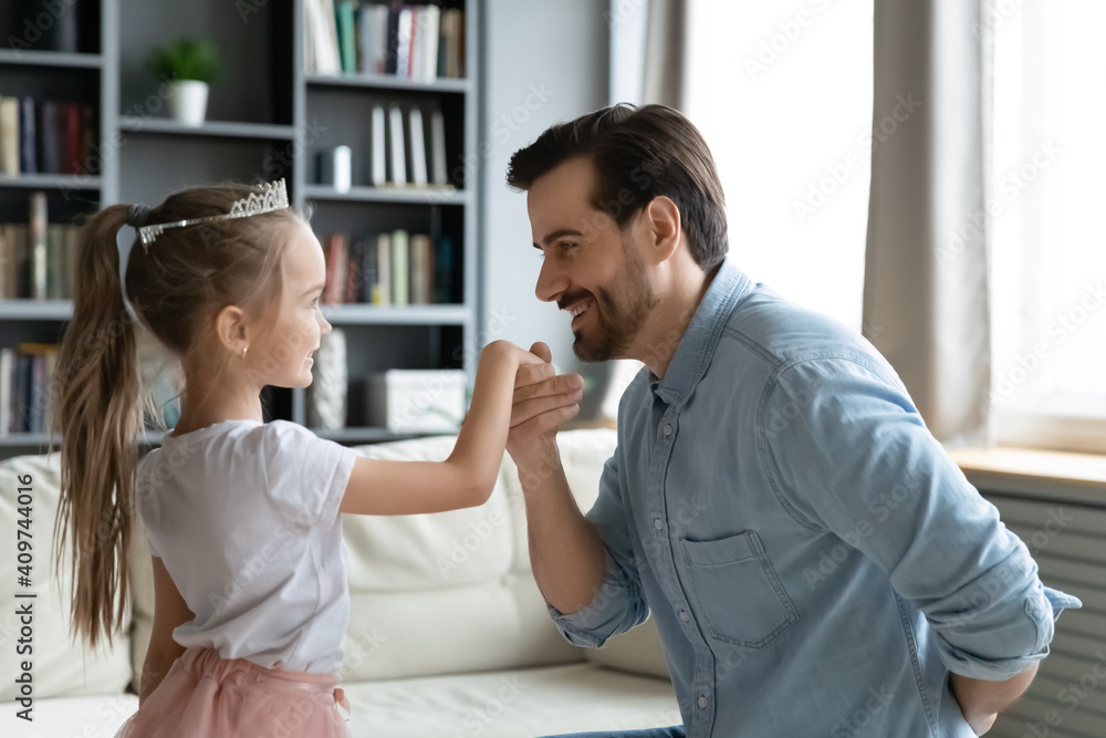 Affectionate young dad kissing hand of cute 6s little kid daughter