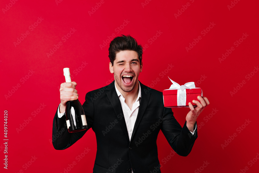 European young man posing with gift and champagne. Smiling guy celebrating valentine's day. European young man posing with gift and champagne. Smiling guy celebrating valentine's day.