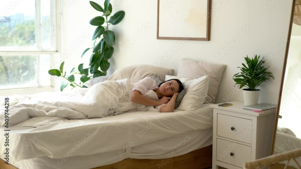Caucasian female using smartphone gadget for checking morning news and notifications after wake up in bedroom, young woman reading received message on cellphone while lying in flat bed Caucasian female using smartphone gadget for checking morning news and notifications after wake up in bedroom, young woman reading received message on cellphone while lying in flat bed
