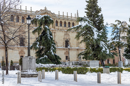 san diego square in the city of alcala de henares snow covered on a sunny day with facade of cisneriana university in the background