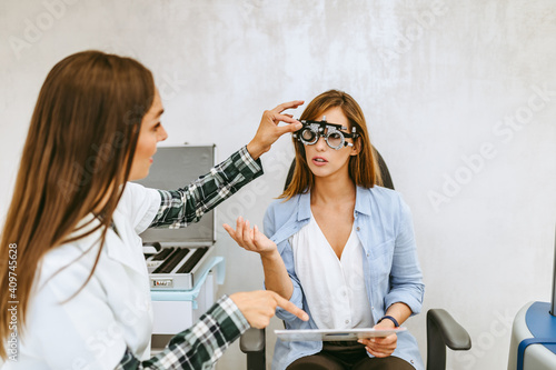 Female optometrist checking patient's vision at eye clinic. Healthcare and medical concept. photo