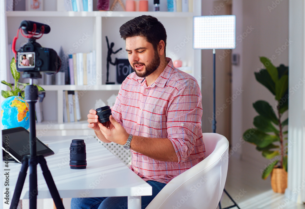 young adult man creating online content for the channel, daily vlog, comparing camera lenses at home young adult man creating online content for the channel, daily vlog, comparing camera lenses at home