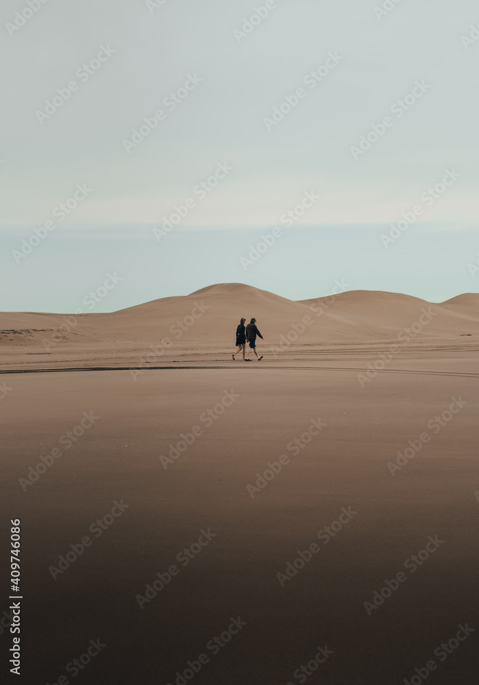 couple walking through the dunes at sunrise