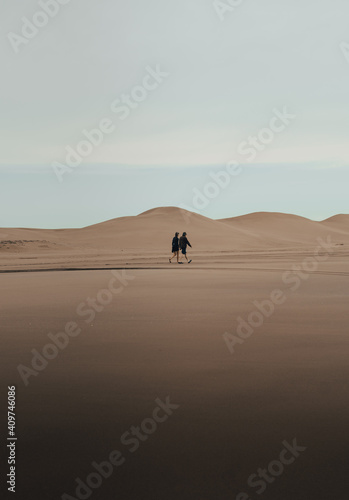 couple walking through the dunes at sunrise