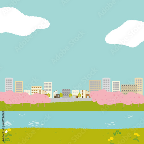 タンポポの生えた河原から見る街並みと桜