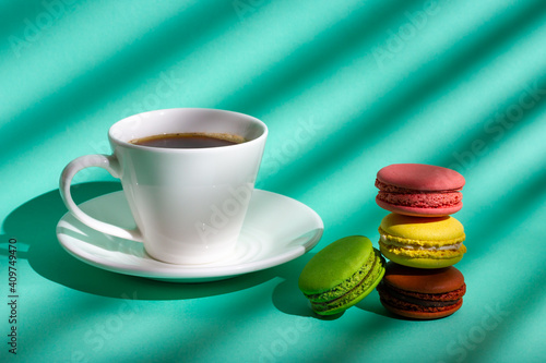 A cup of coffee and colored cookies made from almond flour - macaroon.