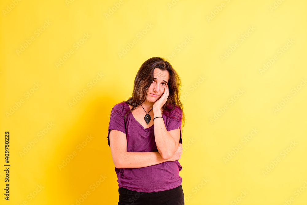 Young woman with anguished and uneasy expression, isolated on yellow studio background. Young woman with anguished and uneasy expression, isolated on yellow studio background.