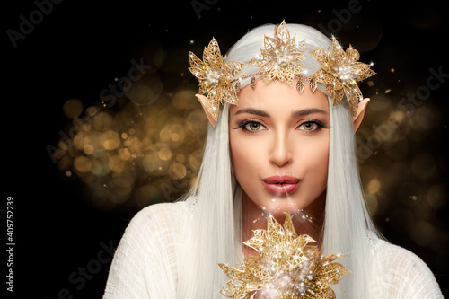 Elf queen with golden flowers in glitters. Young woman with carnival fairy tale costume photo