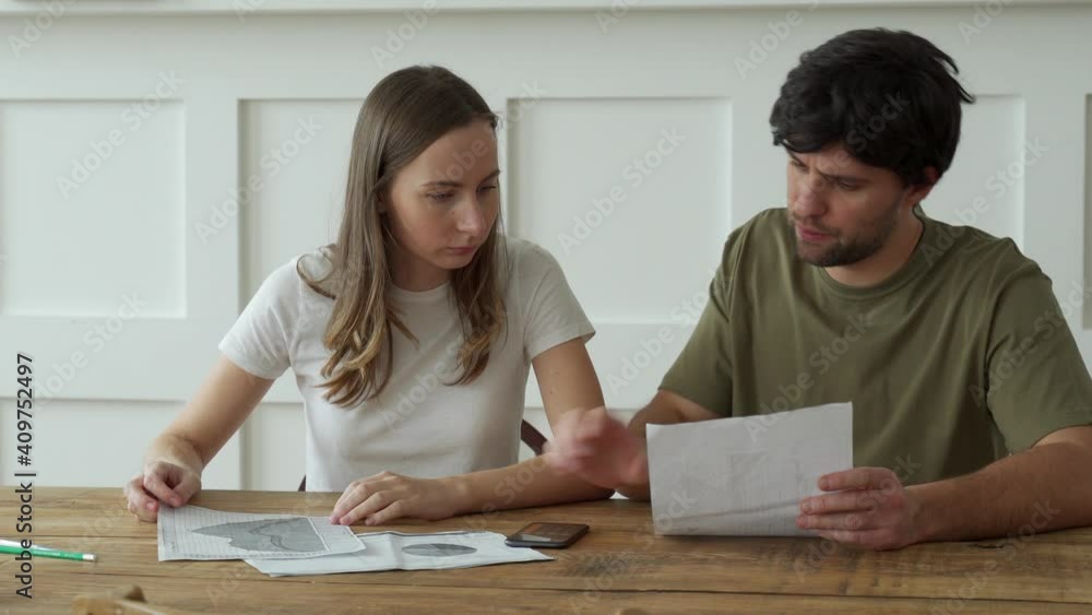 Stressed young couple calculating monthly home expenses, credit card bills payment. 