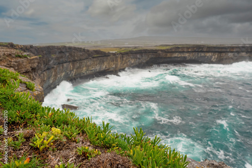 Atlantic ocean and cliff of Inishmore, Aran islands, county Galway, Ireland. Cloudy day, Nobody. Travel and explore nature concept. Powerful wave hits stone coast line.