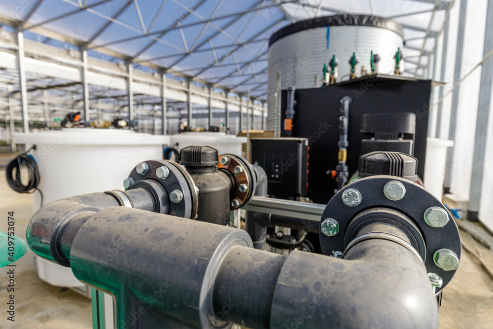 Large industrial water treatment and boiler system in a greenhouse with many pipes and valves Large industrial water treatment and boiler system in a greenhouse with many pipes and valves