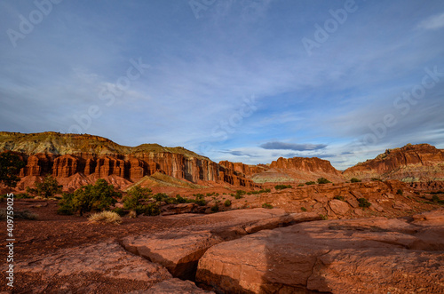 Sunset during golden hour in Southern Utah, sun warming red sandstone, cliffs, mountains, and mesa, and sun