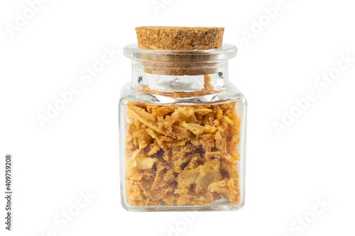 Crispy carmelized fried onion flakes in a glass jar isolated on white background. Spices and food ingredients.