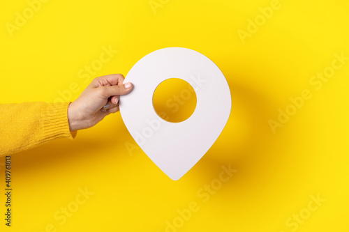 3D location symbol in hand over yellow background