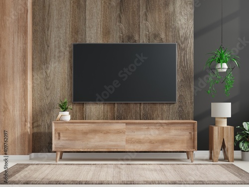 Mockup a TV wall mounted in a dark room with a dark wood wall.