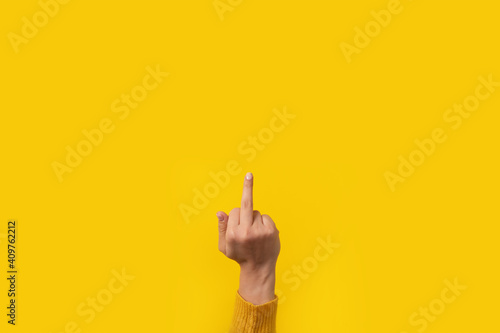 Hand gesture, fuck you symbol, middle finger sign over yellow background